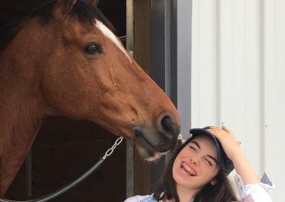 Horse stable with a friendly horse and a smiling girl enjoying her time at Millstone Stables.