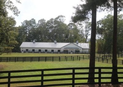 Scenic view of Millstone Stables with riding arena and surrounding trees.