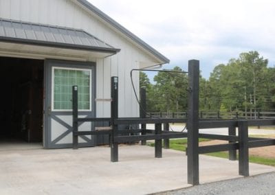 Stable entrance with black fencing and white barn exterior at Millstone Stables.