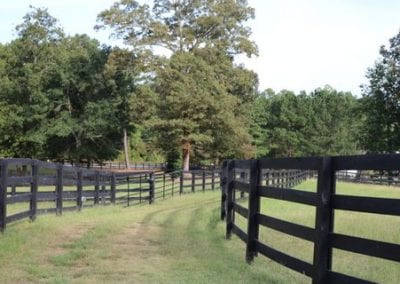 Scenic view of the entrance to Millstone Stables with lush green pastures and fencing.