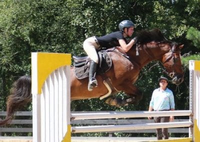 Young rider jumping horse over obstacle at Millstone Stables.