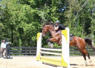 Equestrian rider jumping over obstacle at Millstone Stables.