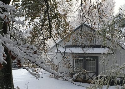 Stable surrounded by snow-covered trees.