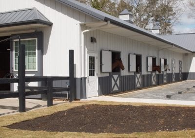 Modern horse stable building with multiple stalls and white exterior.