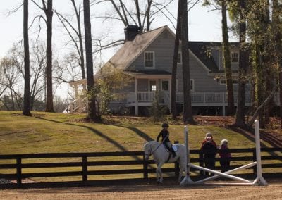 Equestrian riding lesson at Millstone Stables in a scenic outdoor arena.